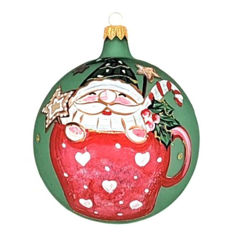 Blown glass ball ornament on a matte green ball with a Santa sitting inside a red hot cocoa cup hand painted on it