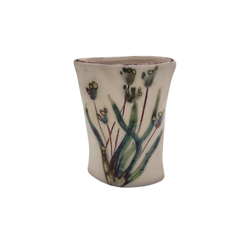 Cream vase with green iridescent flowers.