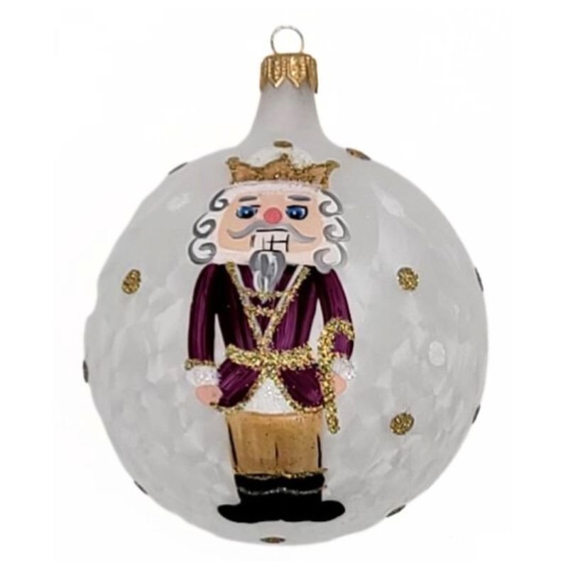 Blown glass ball ornament with a textured matte white background with a nutrcracker prince and gold dots hand painted on it