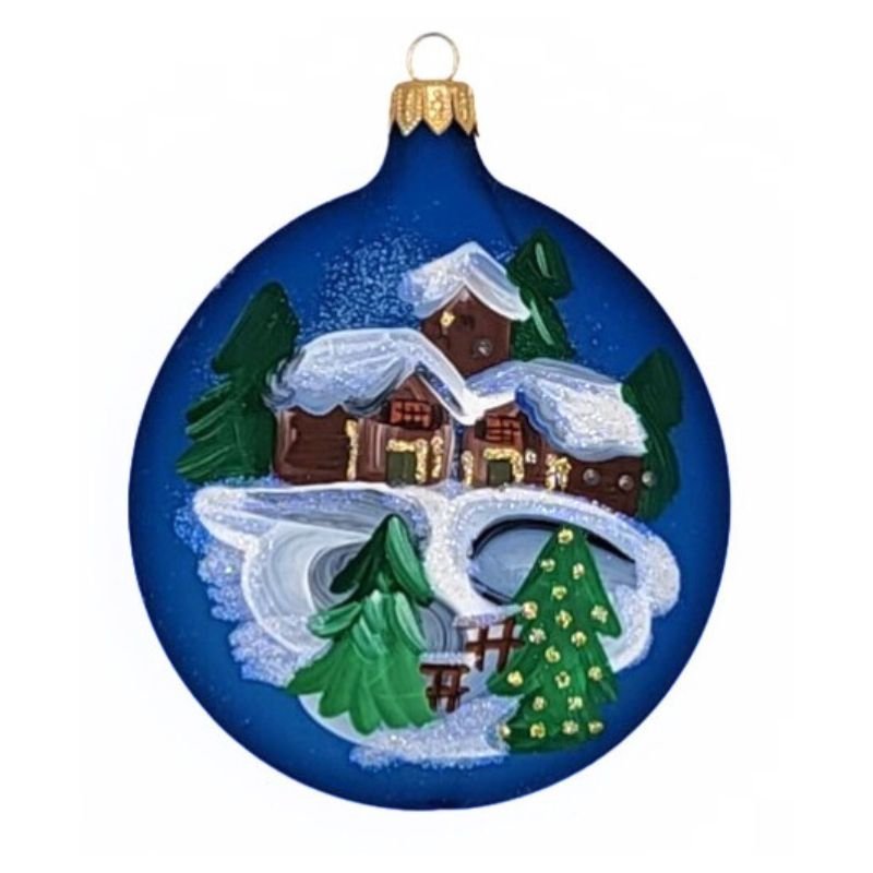 Blown glass round but flat ornament in matte navy blue with a winter  village scene hand painted on it