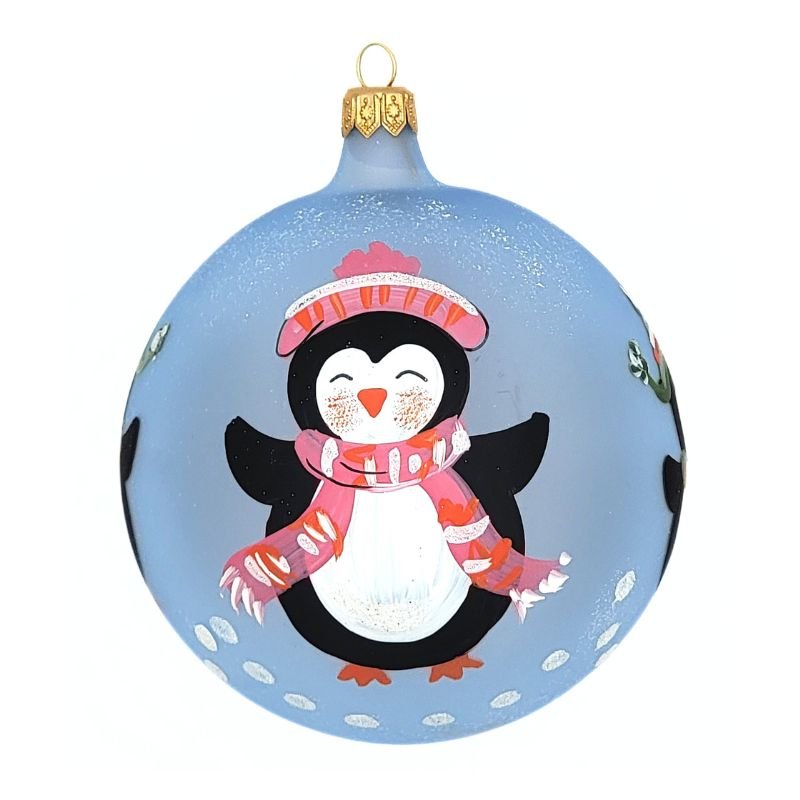 Blown glass ball ornament in light blue with four penguins wearing hats and scarves are hand painted on it