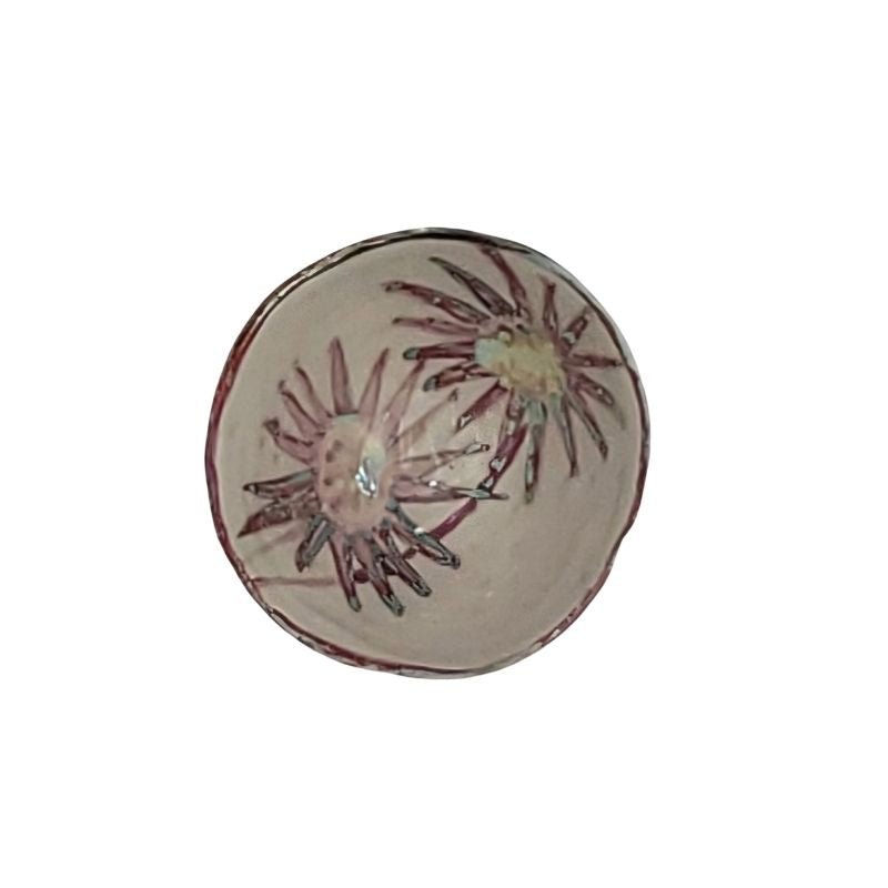 "Hand-painted iridescent bowl with two large sunbursts inside, perfect for holding small items or as a decorative accent"