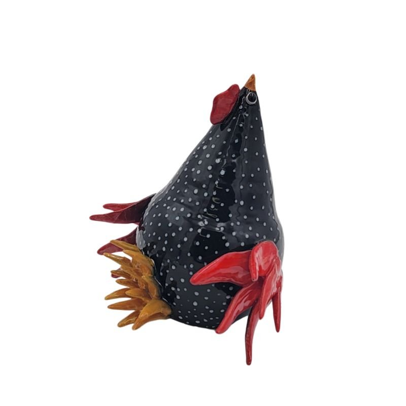 Ceramic black and white polka dot chicken with red side and top feathers and golden tail feathers.