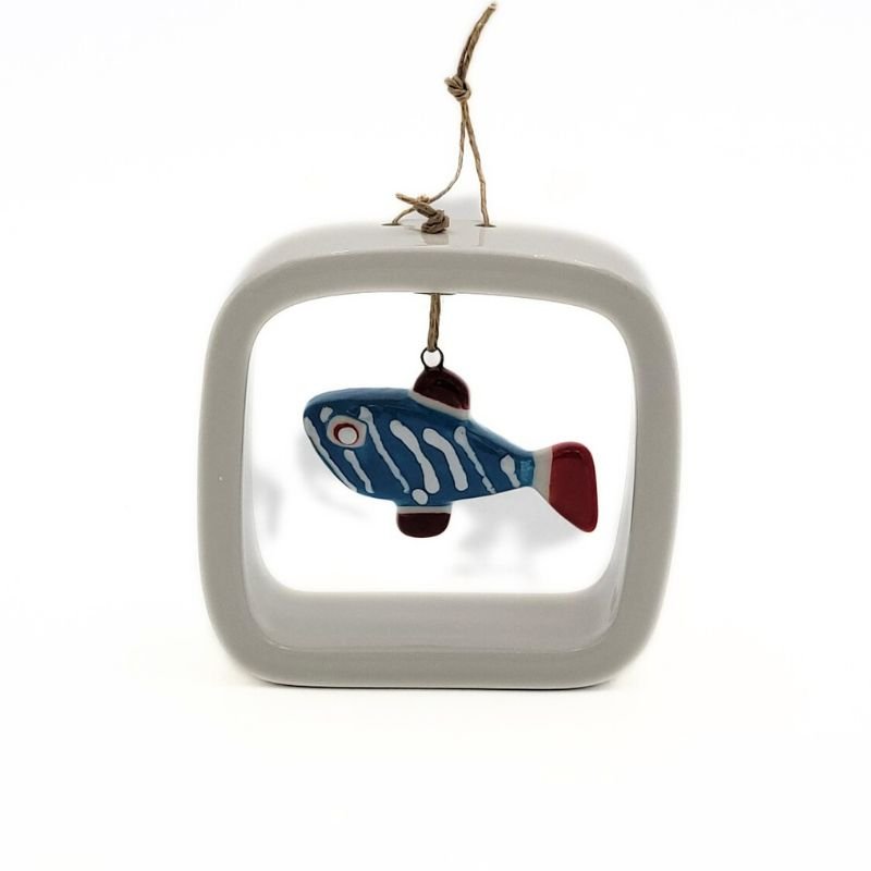 A blue, red and white ceramic fish dangles from an open white ceramic frame.