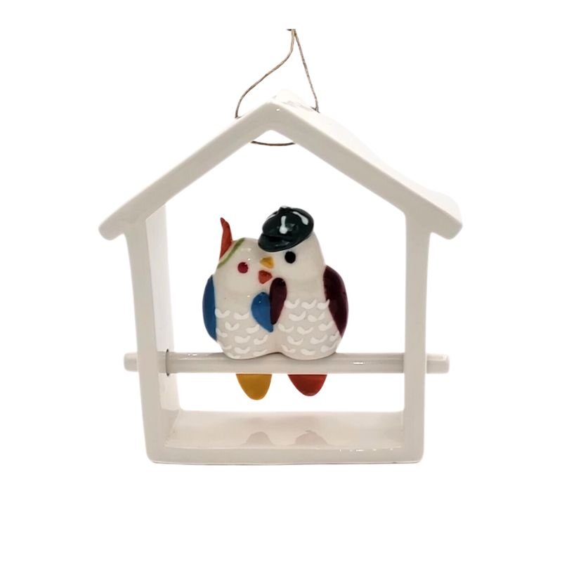 Two ceramic lovebirds sit inside a white ceramic house